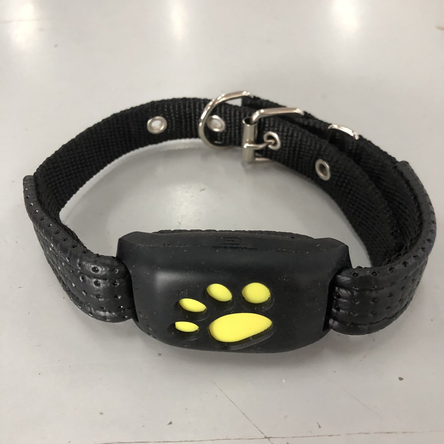 Black dog collar with a yellow paw print on a white background